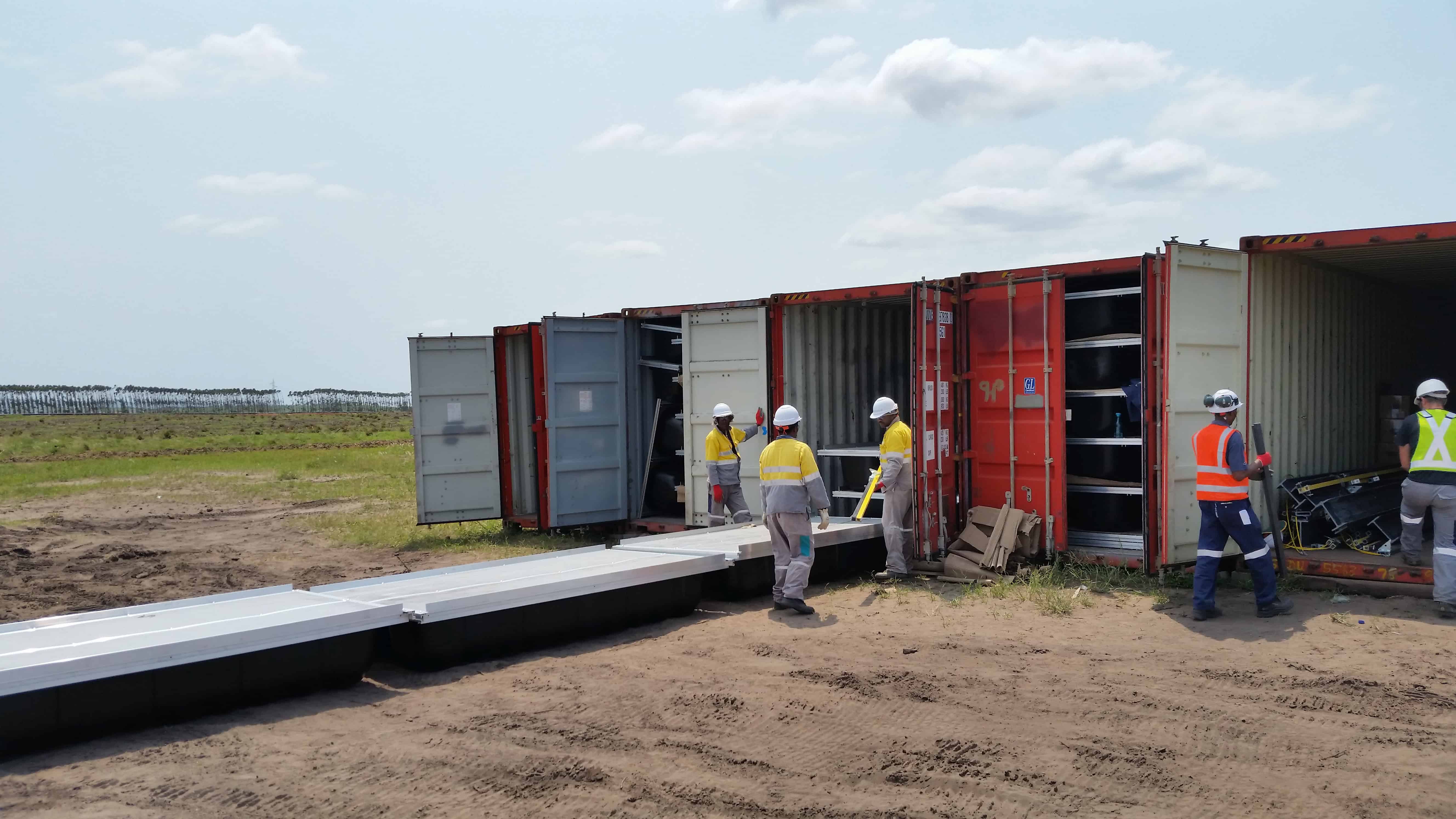 Crews unloading Xrosswater walkway sections from shipping containers on site